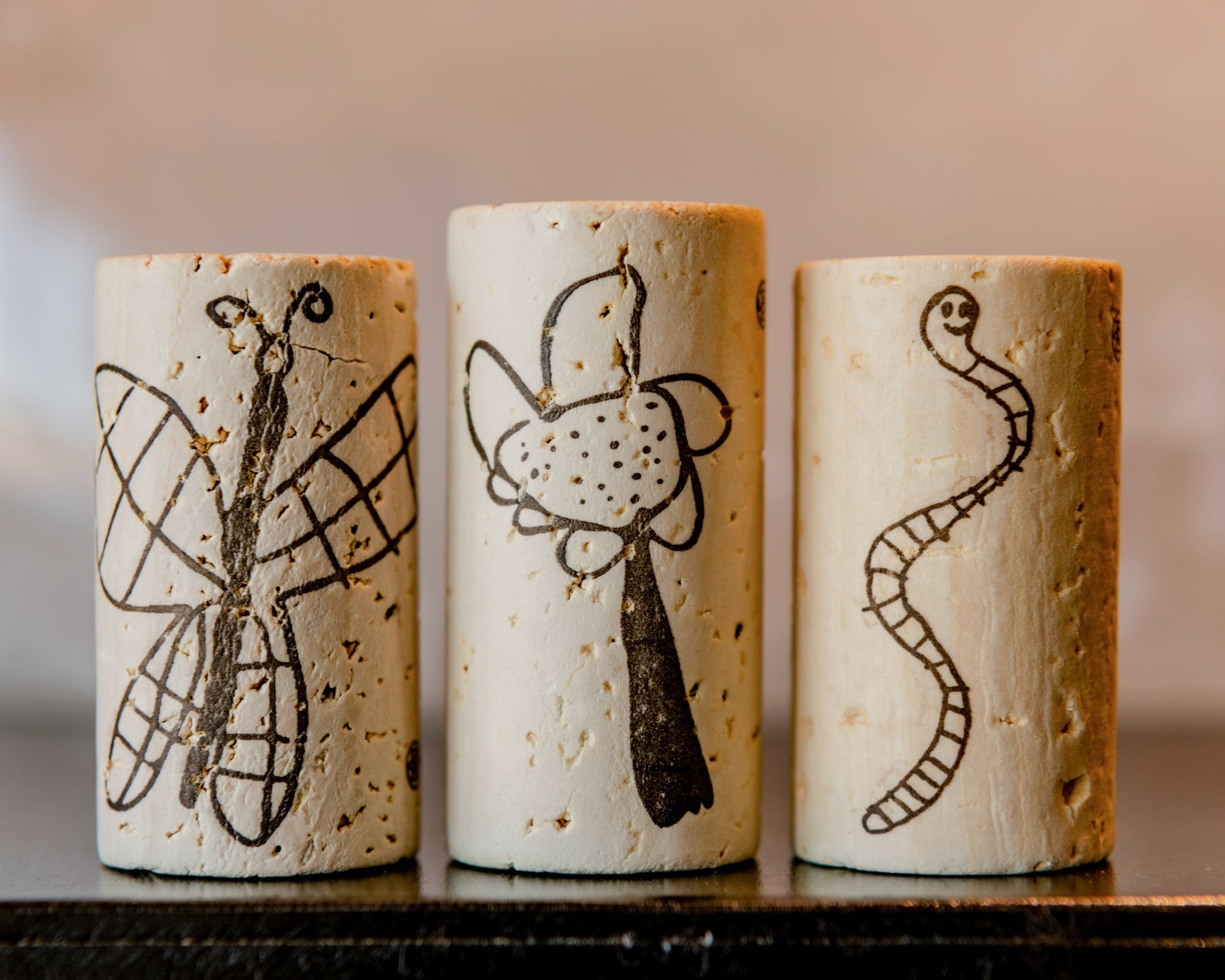 Three wine corks with artistic designs on a blurred background